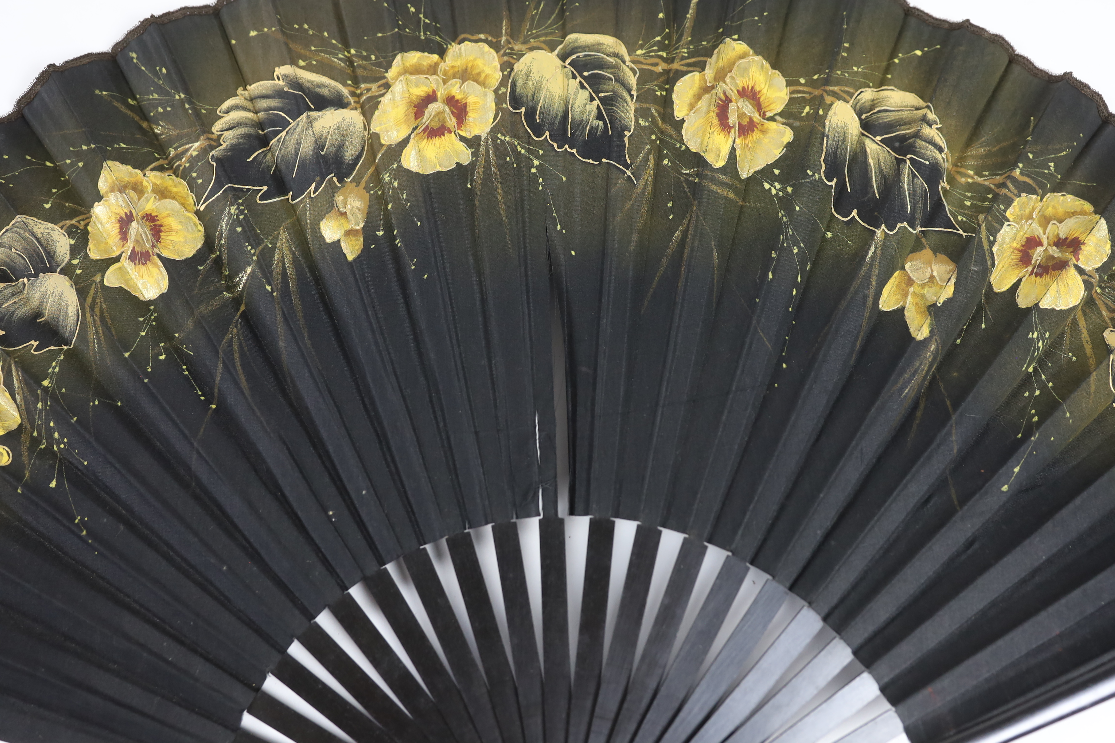 Two early 20th century ebony fans, one cotton leaf, the other hand painted pansies on a fine a silk leaf